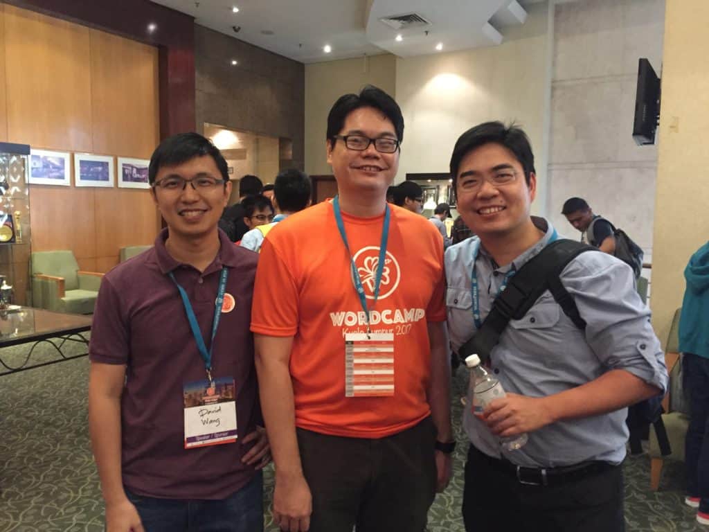 Three men in orange shirts posing for a photo.